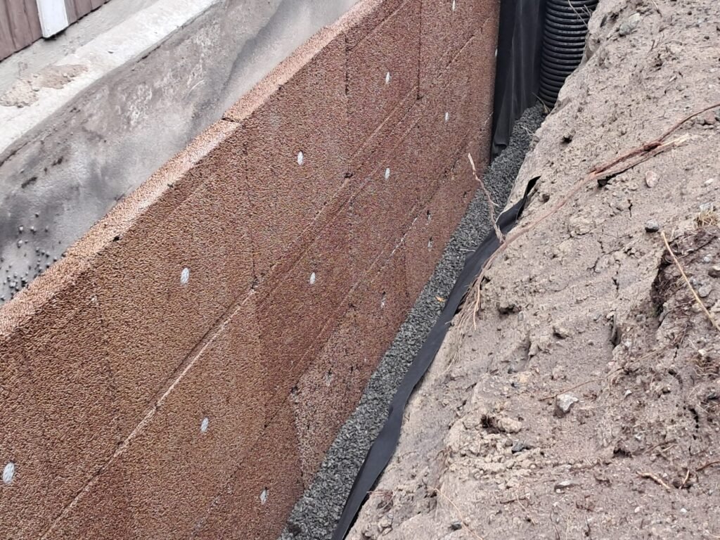 Dränskiva mot grundmuren med makadam, fiberduk och nytt dränrör i schaktet