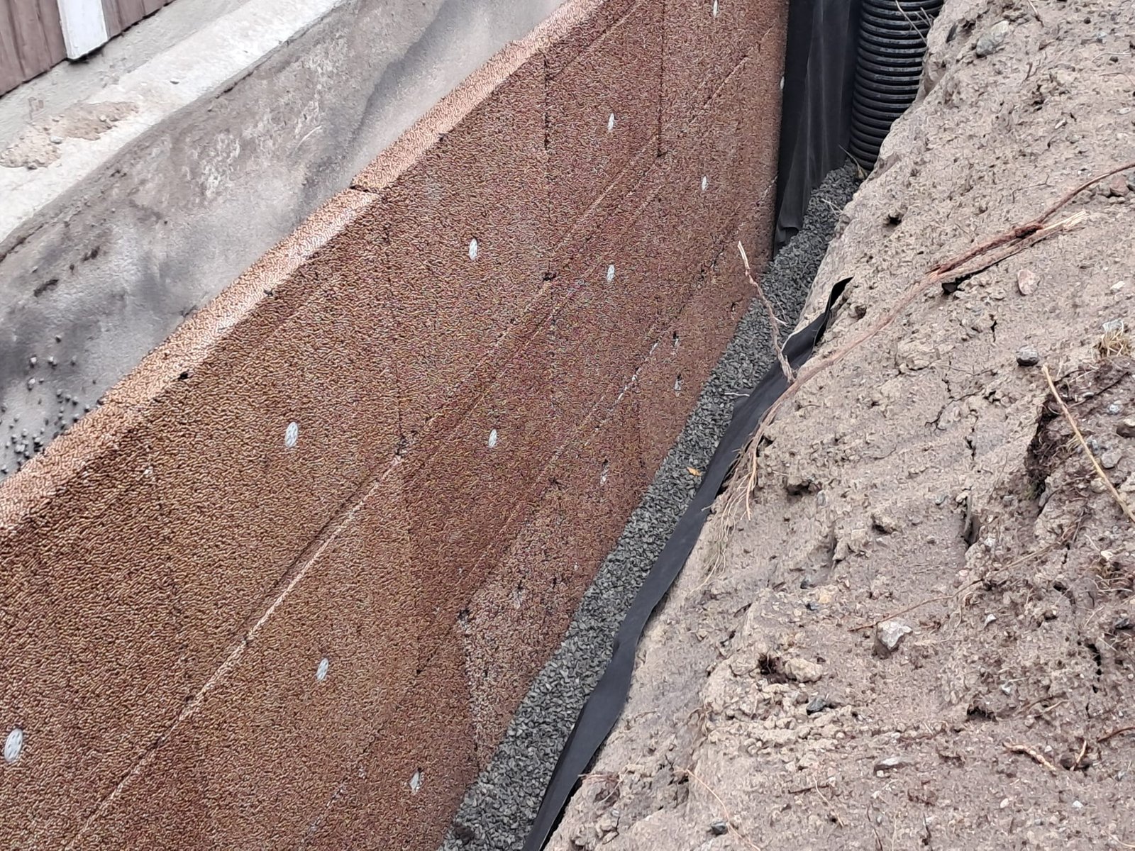 Dränskiva mot grundmuren med makadam, fiberduk och nytt dränrör i schaktet